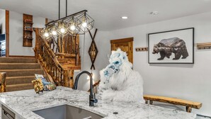 A kitchen with a marble countertop, a sink, and a wooden staircase. - Large Luxury: Fun 4 the Whole Family. 2 min walk to Slopes. Hot Tubs. Pool Table (Steamboat Springs)