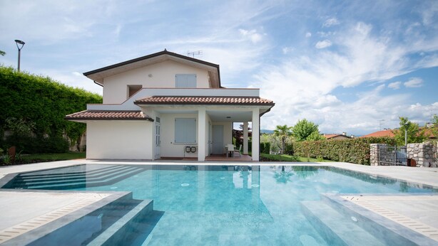 Ein zweistöckiges Haus mit Schwimmbecken davor.