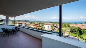 Varanda com vista para uma área residencial, uma mesa com cadeiras e piso de azulejos.