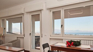Quarto com vista para o mar, uma mesa de madeira, uma cadeira e um radiador.