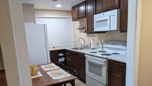 Una cocina con armarios de madera, un refrigerador blanco, un microondas, una estufa y un fregadero.