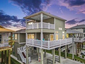 A multi-story building with balconies, a covered outdoor area, and a staircase. - Canal Front | Gated Community, Firepit & Decks (Port Bolivar)