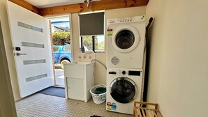 A laundry room with a washing machine, dryer, and a small utility cabinet. - Little Innes - affordable accommodation with a view (PORT ALBANY)