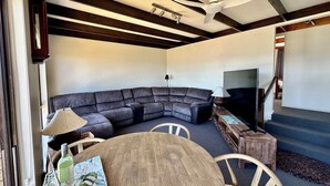 A living room with a sectional sofa, a wooden coffee table, a TV, and a ceiling fan. - Little Innes - affordable accommodation with a view (PORT ALBANY)