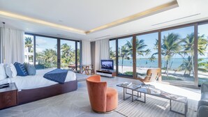Une chambre d’hôtel moderne avec un grand lit, une télévision et une vue sur la plage.