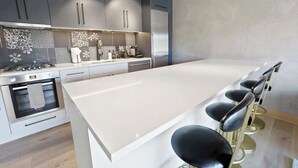 Une cuisine moderne dotée d’un grand îlot central, de tabourets de bar et d’appareils électroménagers en acier inoxydable.