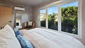 Une chambre avec un grand lit, une chaise, une armoire et une fenêtre donnant sur un paysage verdoyant.