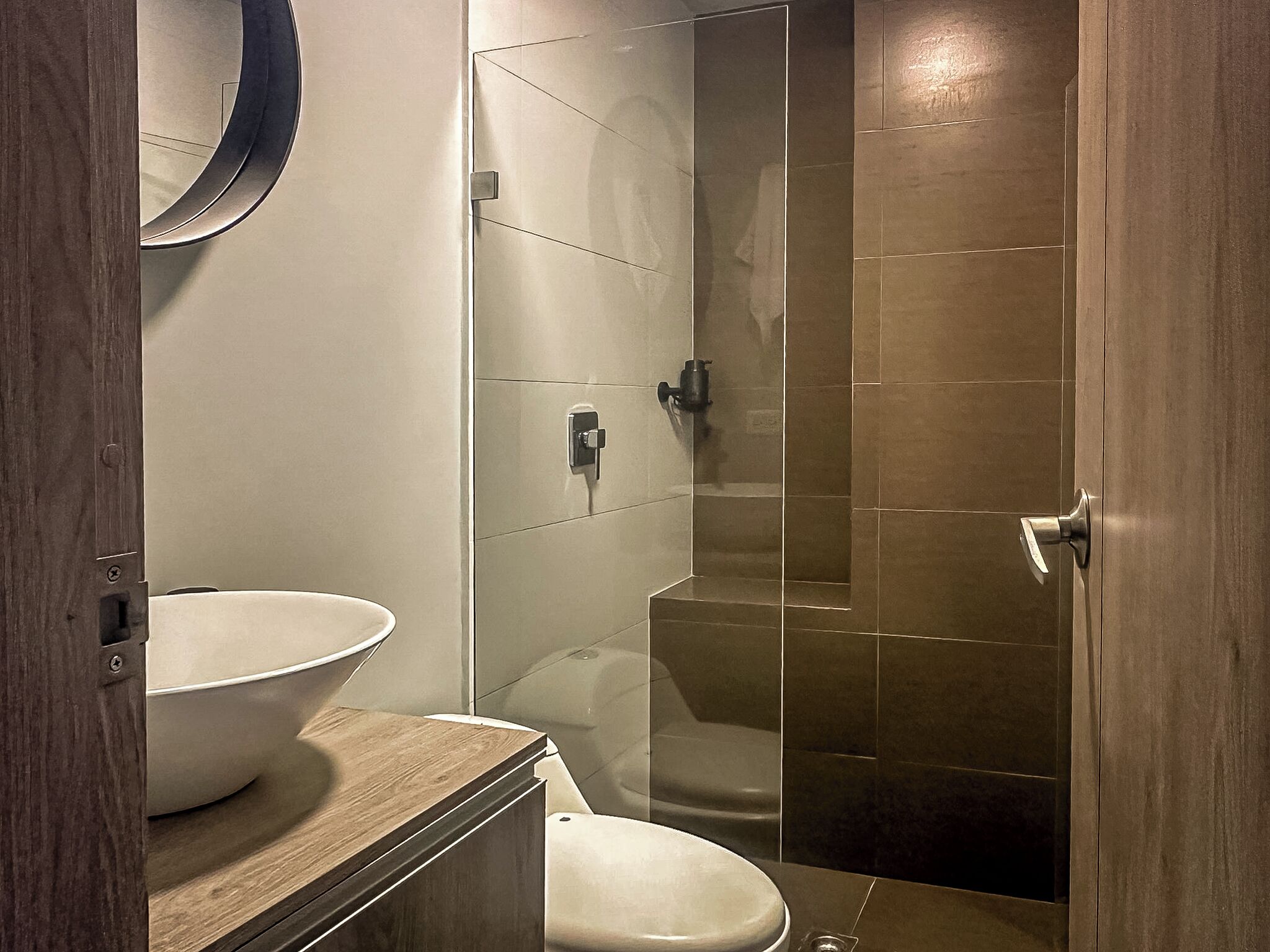 Een moderne badkamer met een groot wit wastafel, een toilet en een douche met glazen wanden.