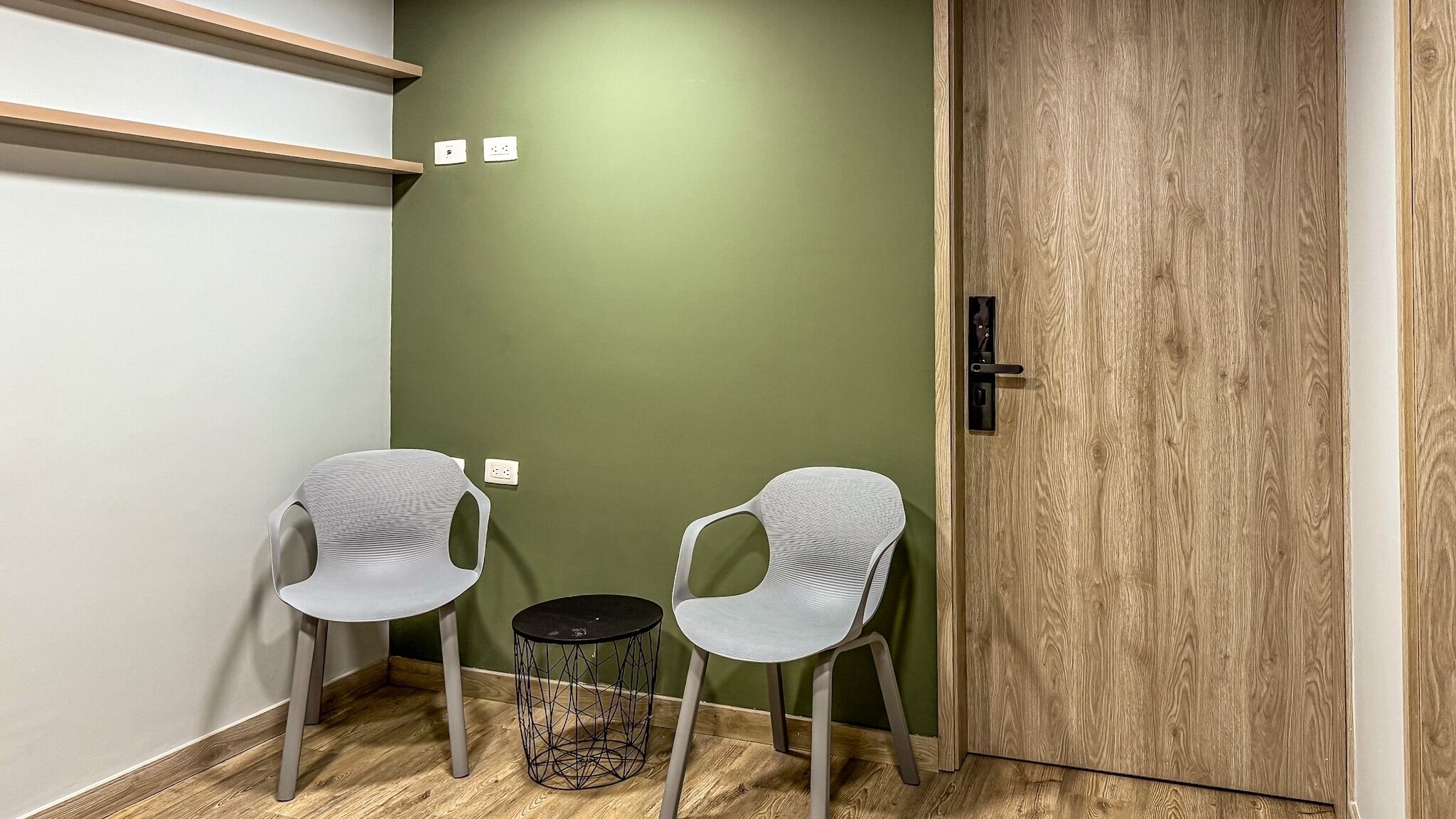 A small room with two chairs, a round table, and a wooden door.