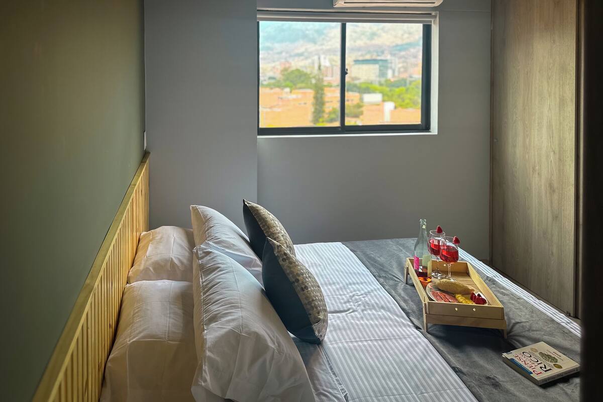 Ein Schlafzimmer mit Bett, Fenster mit Blick und Nachttisch mit Tablett.