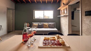 A dining area with a table set for two, featuring a bottle of red wine, two wine glasses, and a plate of sliced meats and cheese. - Edificio Atalanta (Medellín)