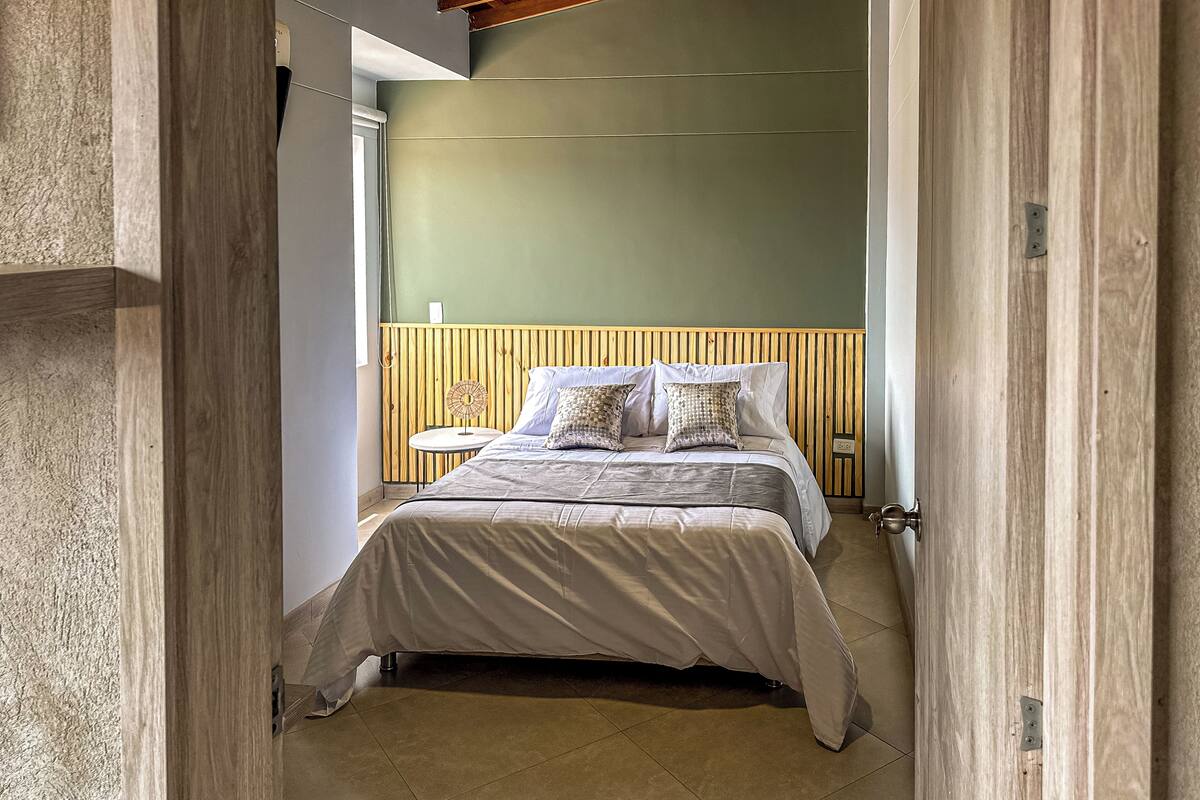 Ein Schlafzimmer mit Bett, Nachttisch und Wandventilator.
