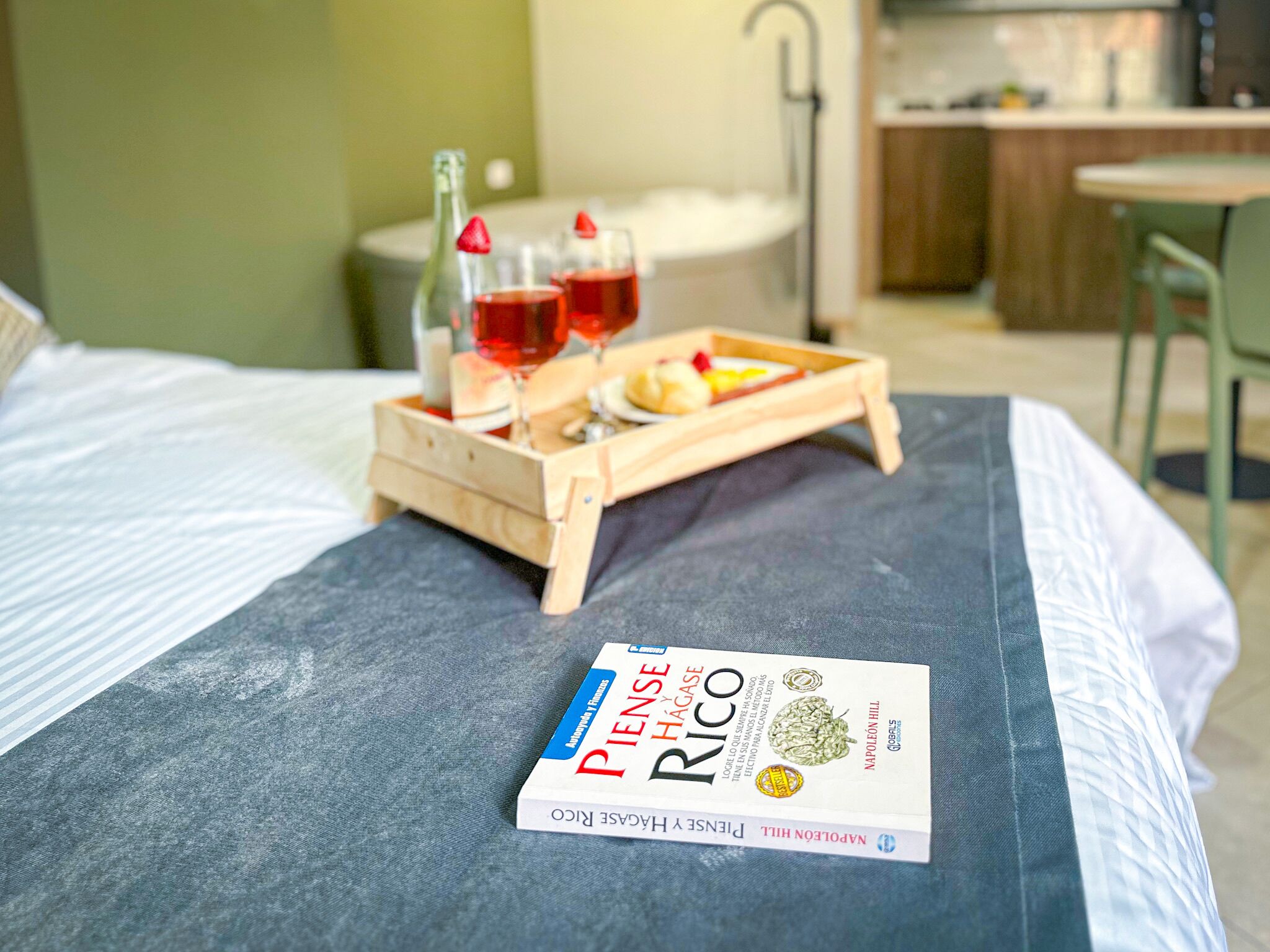 Una cama con una bandeja de comida y bebidas, un almohón y un libro titulado "Pilsen y Hagarico".