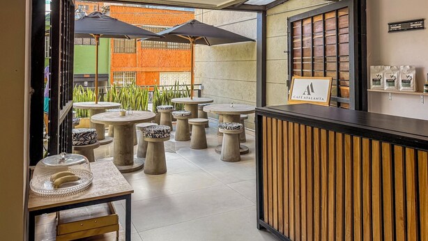 A café with outdoor seating, including round tables and stools, and a wooden reception desk. - Edificio Atalanta (Medellín)