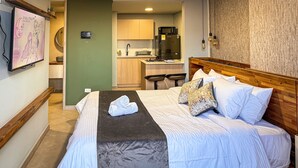 A hotel room with a bed, a small kitchenette, a microwave, and a bar area. - Edificio Atalanta (Medellín)