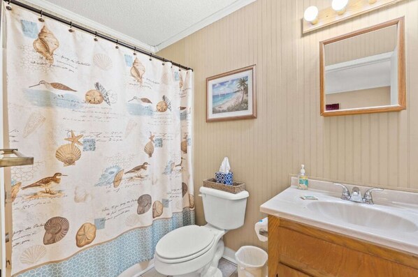 A bathroom with a toilet, sink, and shower curtain with a nautical theme. - Cottage 4 min walk to the beach and Ocean Annies, 2 bed, 2 bath, Shore Dr. area, (Myrtle Beach)