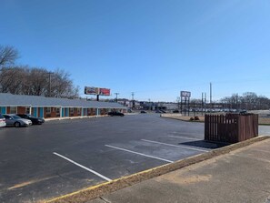 A parking lot with a motel and a billboard advertising a tattoo festival.