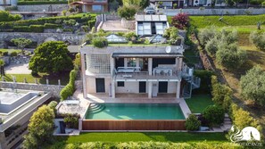 A modern two-story house with a rooftop terrace, a swimming pool, and a well-maintained garden.