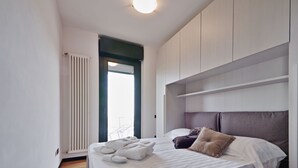Moderni hotellihuone, jossa on sänky, patteri, ikkuna ja kattovalaisin.