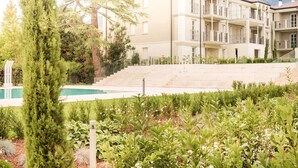 Un immeuble à plusieurs étages doté d’une piscine, entouré de verdure et avec une montagne en arrière-plan.