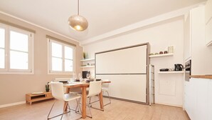 Une cuisine moderne avec une table à manger, des chaises et un luminaire suspendu.