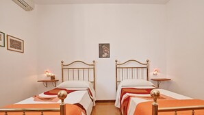 A double room with two single beds, each with a headboard, bedside tables, and wall-mounted lamps.