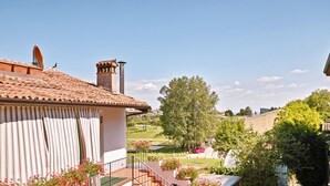 A residential building with a tiled roof, a chimney, and a balcony with potted plants.