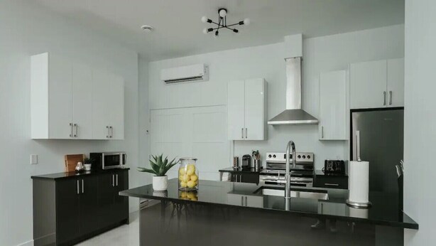 Una cocina moderna con armarios blancos, una isla central, electrodomésticos de acero inoxidable y una encimera negra.