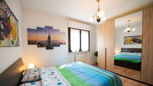 A bedroom with a bed, a window, a radiator, a mirror, and artwork on the walls. - Appartamento Francesca (Sirmione)