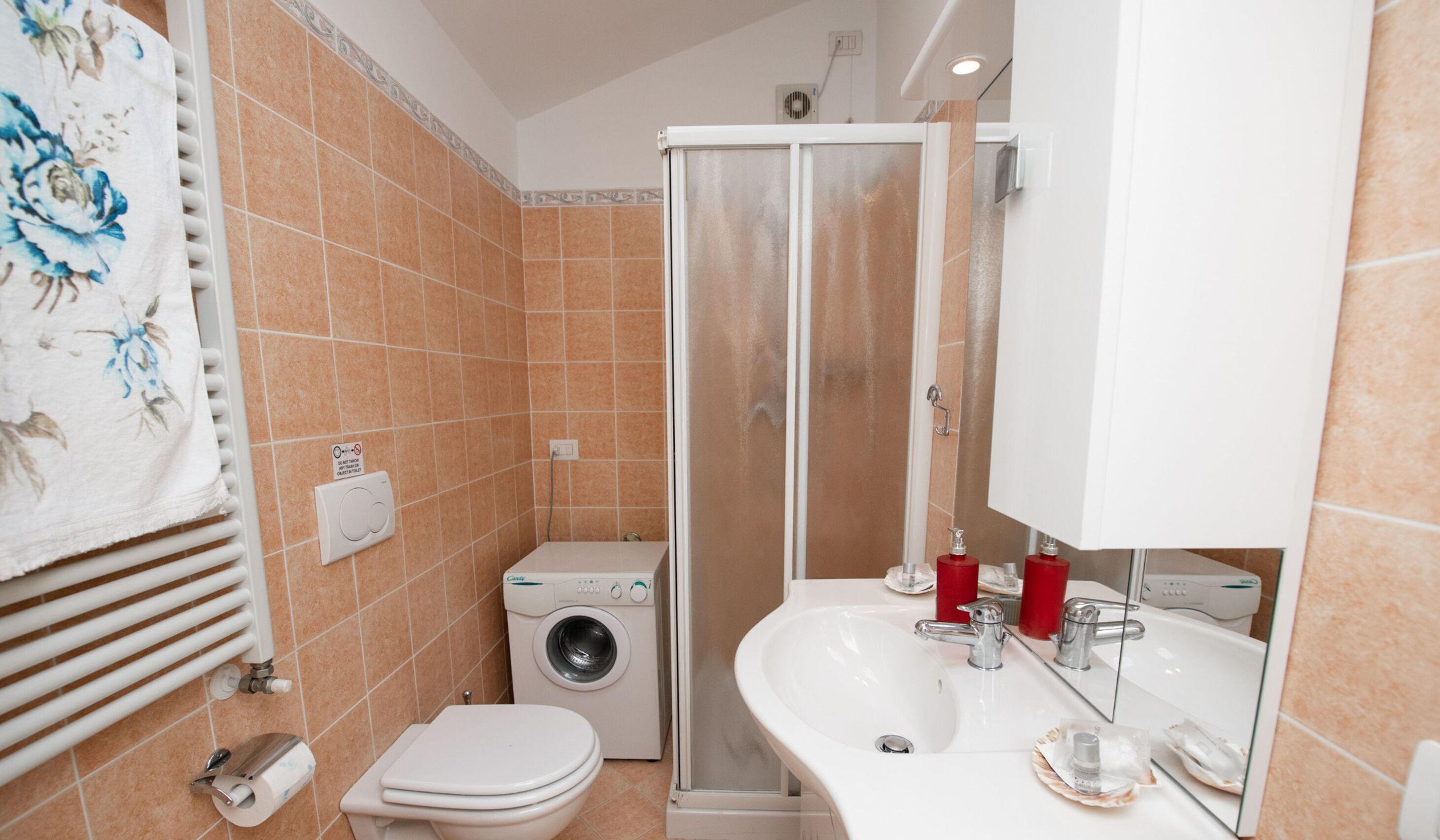 A bathroom with a washing machine, a toilet, a sink, and a shower enclosure.