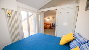 Un dormitorio con una cama grande, un radiador y vista a una habitación contigua con un sofá.