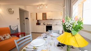 Una mesa de comedor dispuesta con platos, cubiertos y un florero con flores.