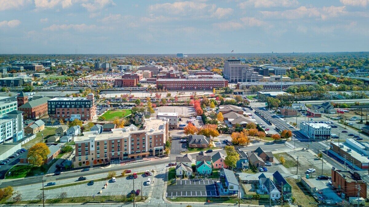 Une vue aérienne d’une ville, avec ses différents bâtiments, ses rues et ses zones de stationnement.