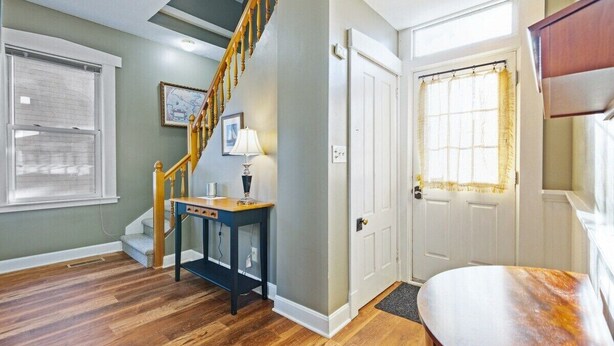 Un escalier menant à un deuxième étage, une porte avec une fenêtre et une petite table avec une lampe.