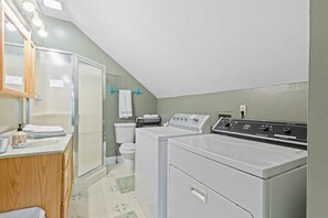 A laundry room with two washing machines, a toilet, and a sink with a mirror above it. - Indy Stadium Villas 710 (Indianapolis)