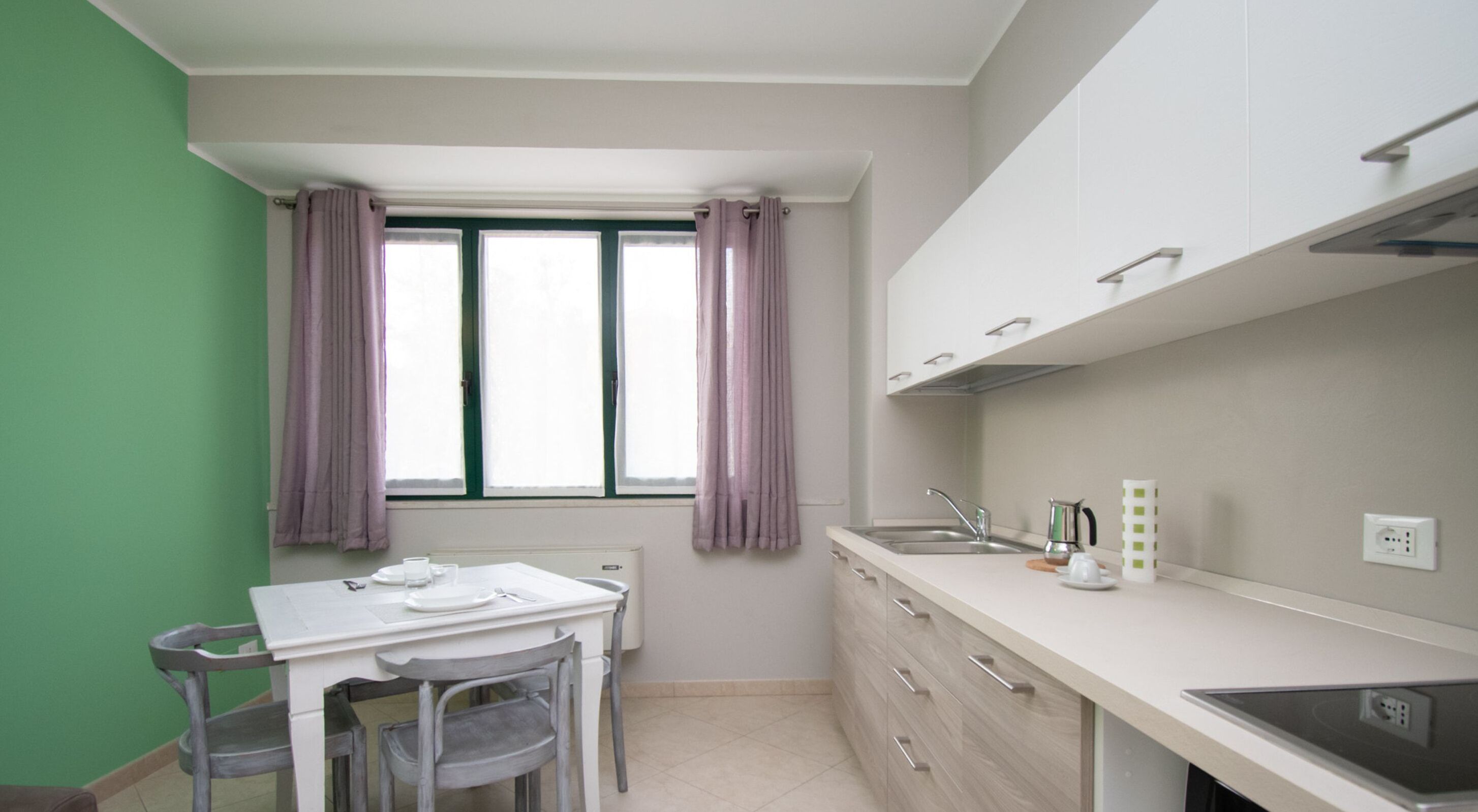 A small kitchenette with a window, a table with chairs, and a sink.