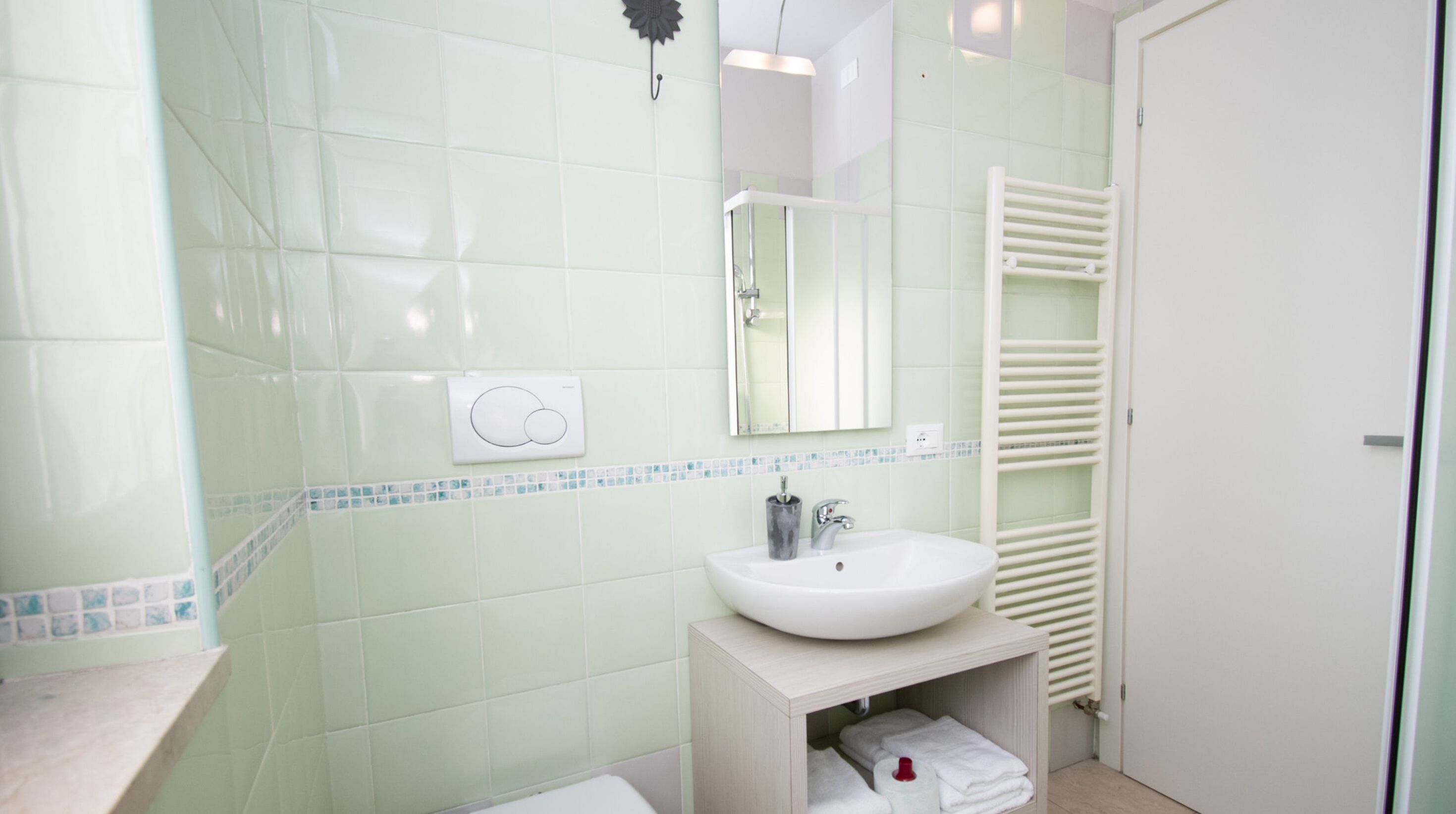 Un baño con un lavabo blanco, un espejo y un perchero para toallas.