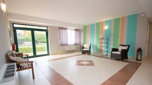 A spacious living area with a large sliding glass door, two wicker chairs, a floor lamp, and a striped wall. - Luxury Martina Appartamenti-7-ibiscus (Moniga del Garda)