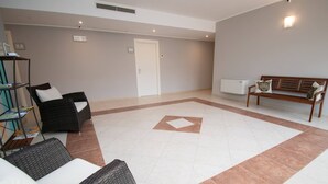 A spacious living area with a tiled floor, a sofa, a bench, and a bookshelf. - Luxury Martina Appartamenti-7-ibiscus (Moniga del Garda)