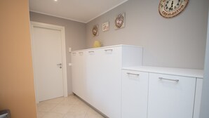 Un pasillo con una puerta blanca, un armario blanco con cajones y un reloj de pared.