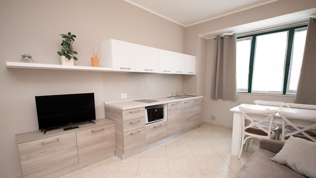 Una cocina moderna con horno empotrado, televisor y ventana con cortinas.