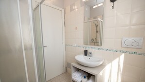Un baño con lavamanos blanco, espejo y ducha.