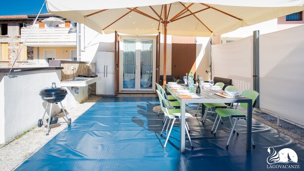 A rooftop patio with a dining table, chairs, and a barbecue grill. - Appartamento Lilli in Manerba del Garda (Manerba del Garda)
