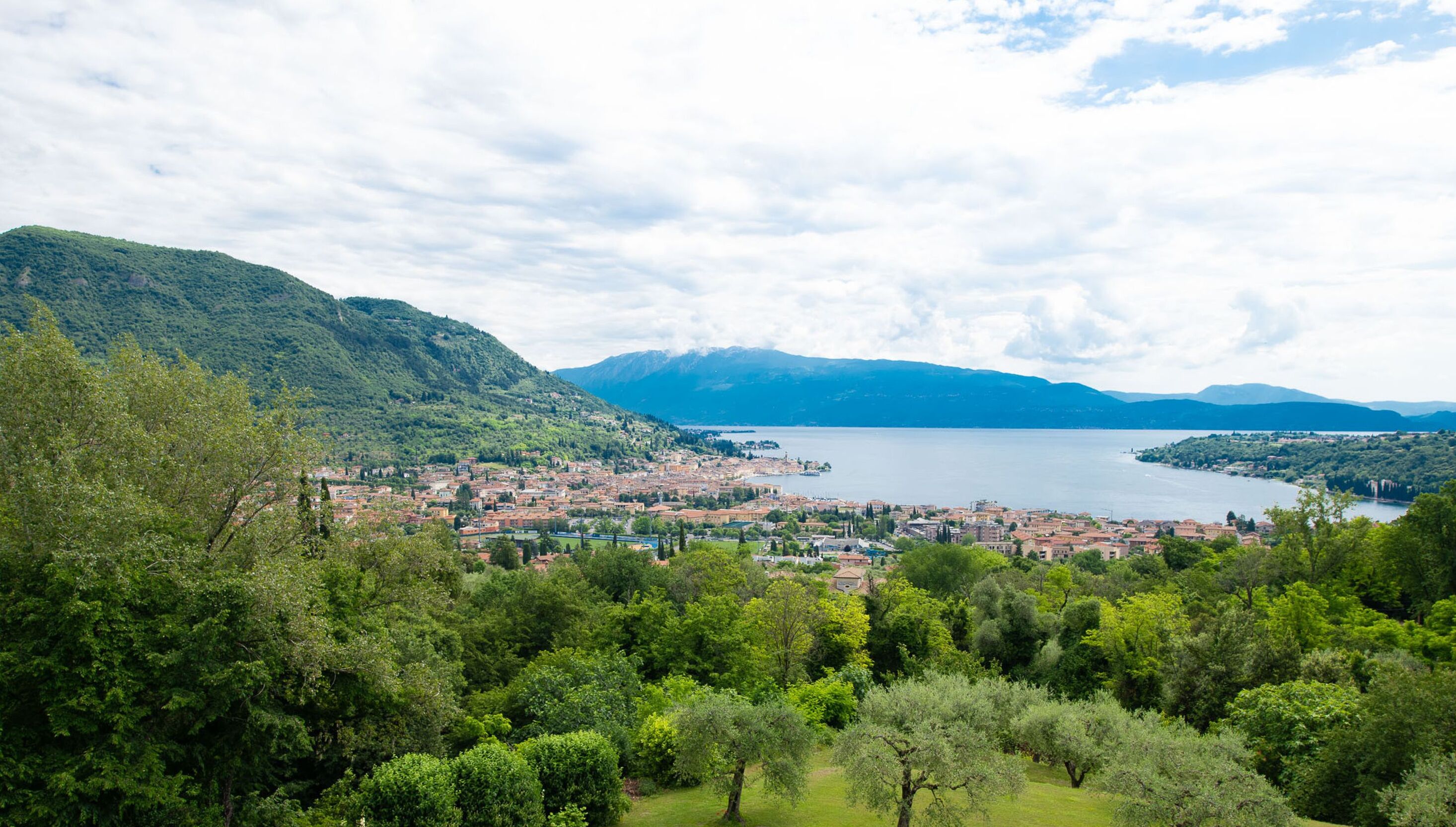 Eine Stadt mit einem See, umgeben von Bergen und üppiger Vegetation.