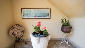 Un panneau d’accueil, un tableau encadré et deux plantes en pot, le tout posé sur un sol carrelé.