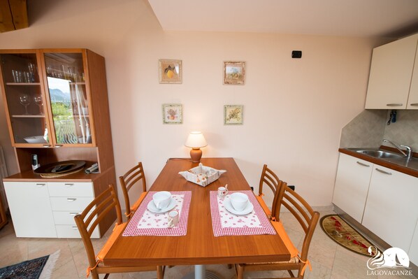 Una mesa de comedor con dos sillas, una lámpara y una zona de cocina con armarios y un lavabo.