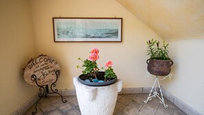 A welcome sign, a framed picture, and two potted plants on a tiled floor. - Feeling House - Appartamento Provenzale (Salò)