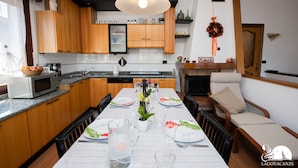Een moderne keuken met houten kastjes, een eettafel voor vier personen en een open haard.