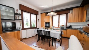 Een moderne keuken met houten kastjes, een eettafel gedekt voor vier personen, en een groot raam dat natuurlijk licht biedt.