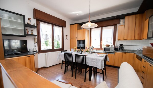Una cocina moderna con armarios de madera, una mesa de comedor lista para cuatro comensales y un amplio ventanal que proporciona luz natural.